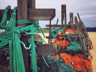 Fishing nets and gear stacked on weathered wooden structures at the beach