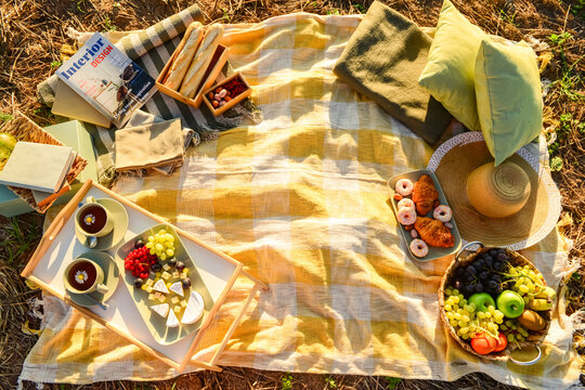 Picnic with tasty food and tea in field at sunset, top view