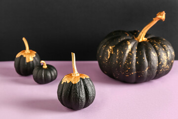 Painted pumpkins on pink table near black wall