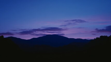 Fototapeta premium Mountain landscape bathed in twilight hues of deep blue and fading sunset colors. 
