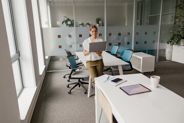 A young professional works on a laptop in a bright, modern office that fosters creativity and productivity
