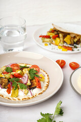 Plate of tasty pita bread with grilled vegetables on white background