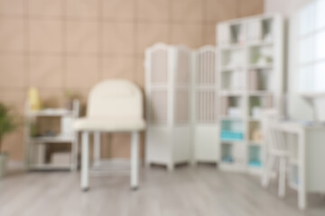 Blurred view of medical office with couch, shelf units and folding screen