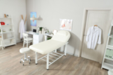 Blurred view of medical office with couch, doctor's workplace and door