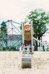 A joyful child plays on a sandbox excavator at a vibrant playground with a colorful climbing...