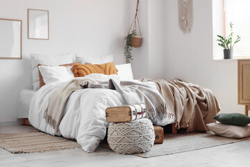 Big comfortable bed and pouf with suitcase in bedroom