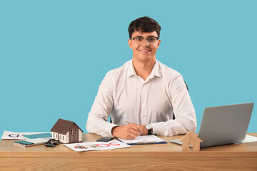 Male real estate agent working at table on blue background