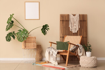 Armchair with cushion, plaid and Monstera houseplant in interior of living room