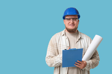 Young male engineer with clipboard and drawing on blue background