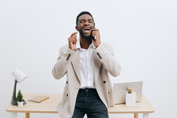 Smiling man talking on smartphone in modern office setting with white wall background, tidy desk...