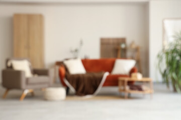 Blurred view of living room with comfortable sofa, table and armchair