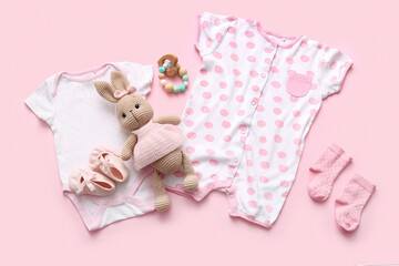 Baby clothes with accessories and toy bunny on pink background