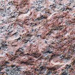 A detailed shot of a textured granite surface with various colors and natural patterns. The surface appears rough and weathered