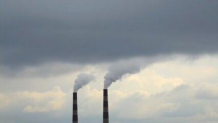 Industrial smokestacks releasing vapor into a cloudy sky, conveying an environmental message with muted tones.