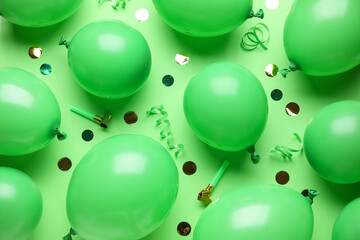 Many air balloons with party whistles and confetti on green background