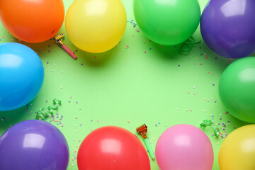 Frame made of air balloons with party whistles and confetti on green background