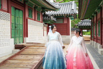 Seoul, June 2025: Two Korean women in their twenties stroll through Gyeongbokgung Palace's halls...