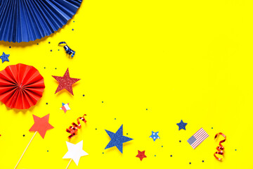 Paper fans with stars and confetti in colors of USA flag for Independence Day on yellow background