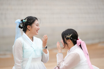 In Seoul in June 2025, two Korean women in their twenties wear pink and sky-blue hanbok as they...