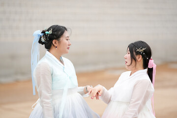 In Seoul in June 2025, two Korean women in their twenties wear pink and sky-blue hanbok as they...