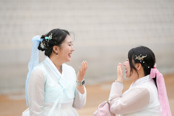 In Seoul in June 2025, two Korean women in their twenties wear pink and sky-blue hanbok as they...