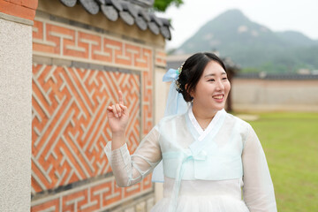 In Seoul in June 2025, two Korean women in their twenties wearing pink and sky-blue hanbok stand in...