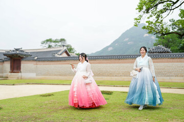 In Seoul in June 2025, two Korean women in their twenties wear pink and sky-blue hanbok as they...