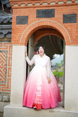In Seoul in June 2025, two Korean women in their twenties wearing pink and sky-blue hanbok stand in...