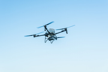 A quadcopter drone flying in the clear blue sky