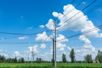 Clear blue sky with white clouds and power lines in the field