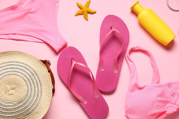 Female swimsuit with flip flops, handbag and sunscreen on pink background