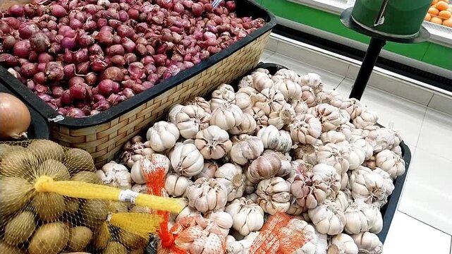 Bandung, Indonesia - July 24th 2025; A woman shopping for shallots and garlic at the supermarket