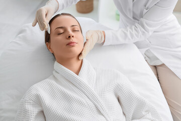 Naklejka premium Young woman receiving facial massage in spa, skincare treatment and relaxation, beauty and wellness