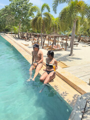 Couple relaxing by infinity pool with cocktails at tropical resort