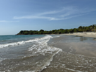 Tropical beach shore with waves gently rolling on the sand in monterrico, guatemala