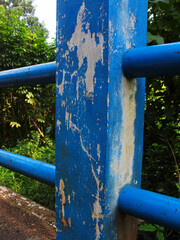 Close up of the blue bridge railing with paint starting to peel.