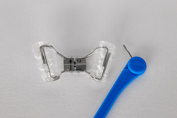Orthodontic palatal expander and blue adjustment key on white background. Removable dental...