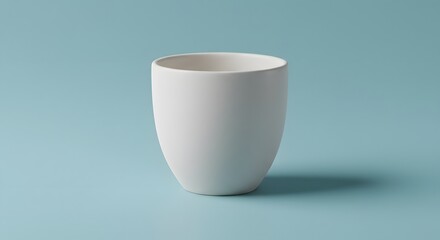 A simple, elegant white ceramic cup stands against a light blue background, empty.