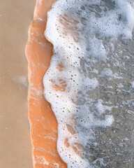 Fototapeta premium Close-up of ocean wave foam on sandy beach