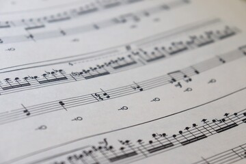 Fototapeta premium A white sheet with a musical partition. Musical notes on a sheet of music paper. Music notes as background with a close-up view.