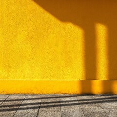 A vibrant yellow wall casting shadows from the sun