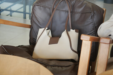 Stylish handbag rests on a leather chair, lost handbag concept 