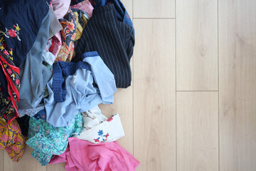 Messy pile of clothing on light hardwood floor