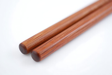 Close up of two wooden chopsticks with a subtle grain pattern against a clean white background
