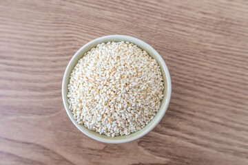Sesame seeds in a bowl on wooden table background. Top view. Flat lay