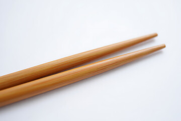 Obraz premium Pair of natural light brown wooden chopsticks resting on a clean white background in a close up shot