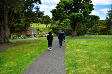 Some tourists are walking towards the Whangarei Falls location in New Zealand.