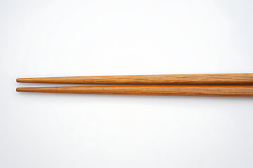 Obraz premium Pair of natural wooden chopsticks resting horizontally against a clean white background isolated studio shot