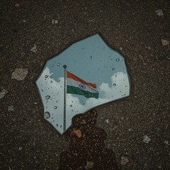 Indian Flag Reflected in Broken Glass Shard on Pavement After Rain for Symbolic Scene