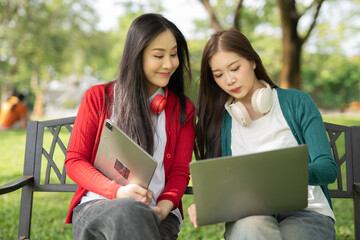 Fototapeta premium Smiling young Asian student wearing headphones talking in online chat using laptop.